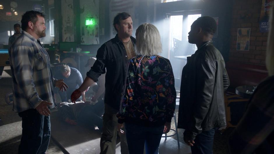 Two patrons stop Liv and Clive from approaching the dying man.