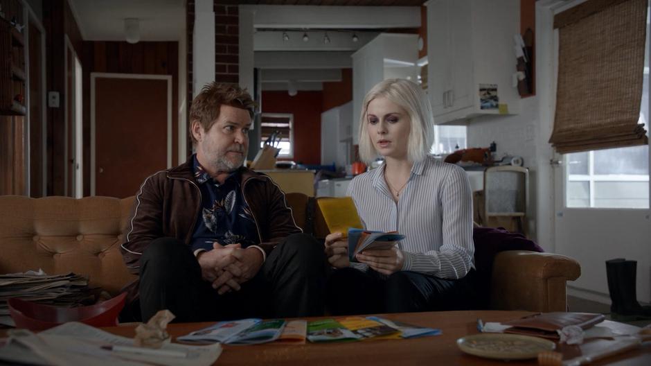 Martin Roberts looks at Liv as she shows him the various brochures for addiction treatment programs.
