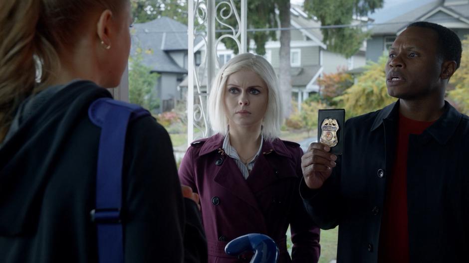 Clive holds up his badge and introduces Liv and himself to Emily Klein at the front door.