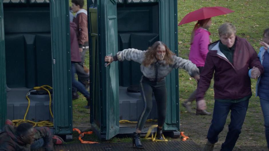 A feral Sloane Mills bursts from one of the port-a-potties and runs towards festival guests.