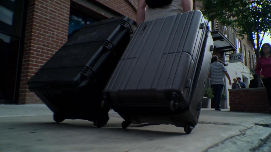 Gregory Sallinger walks down the street dragging two large suitcases.