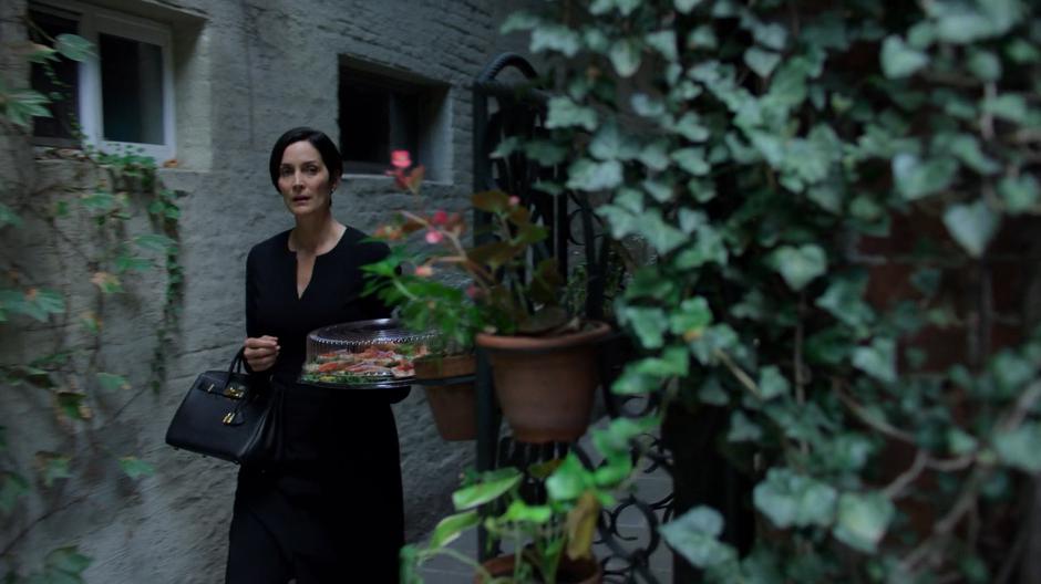 Hogarth walks into the courtyard holding her tray of bagels.