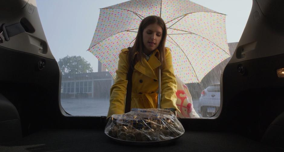 Stephanie takes a plate of snacks from her trunk in the rain.