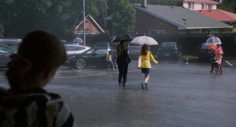 Stacy watches as Emily and Stephanie walk through the rain to their cars.