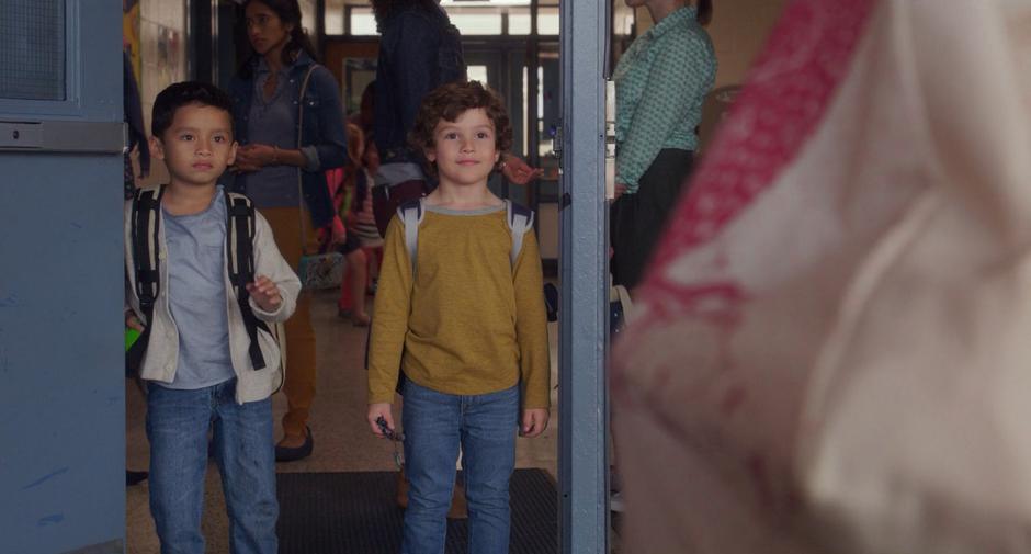 Nicky and Miles look up at Stephanie as she greets them at the door of the school.