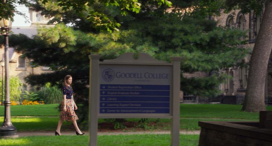 Stephanie walks across campus past the Goodell College sign.