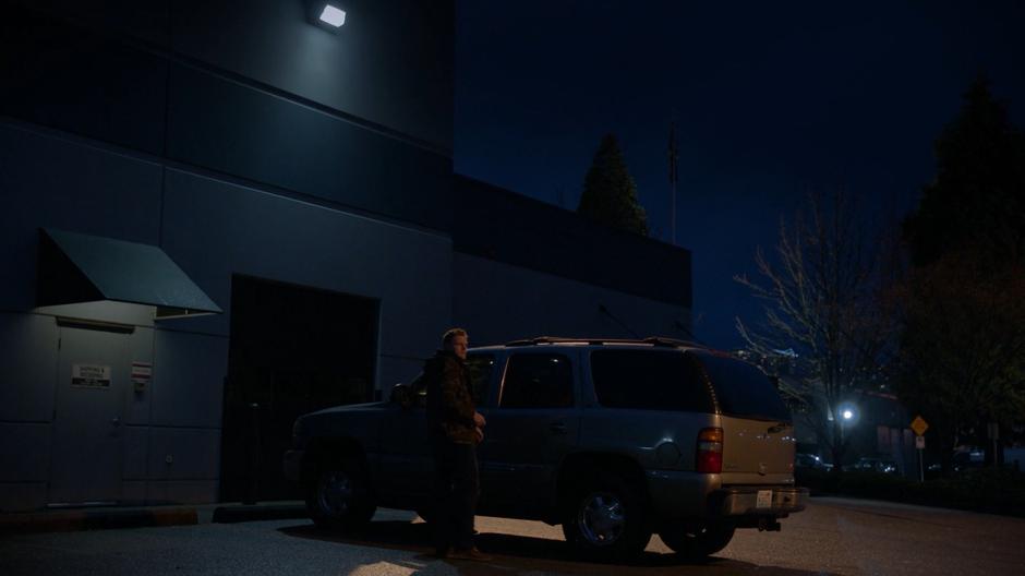 Stan looks around after parking his car outside the garage at night.