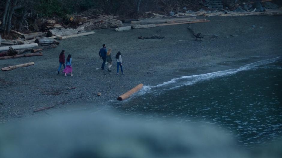 Maddie, Ryn, and the three other mermaids walk down the beach.