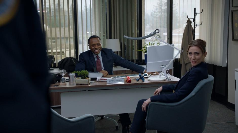 Clive laughs at his desk while Dale responds to the officer.