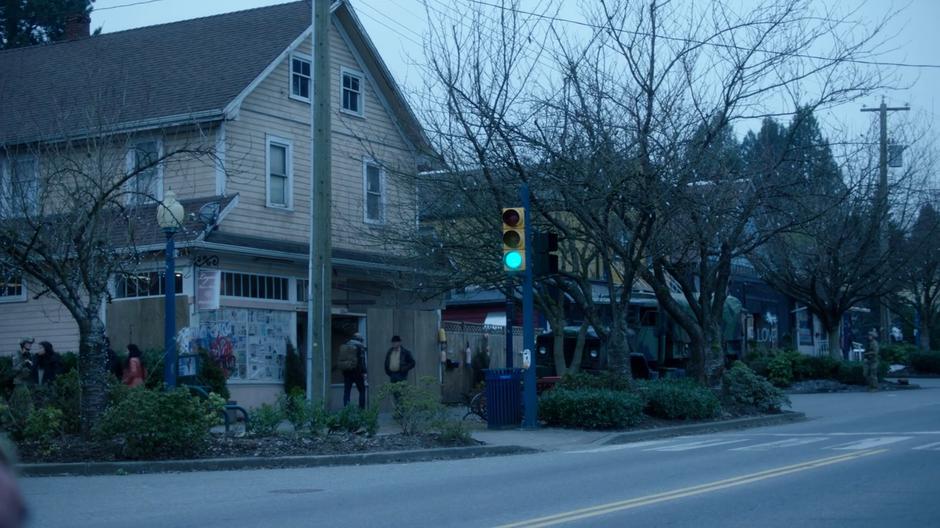 Ben walks down the street past a military truck towards the shop.