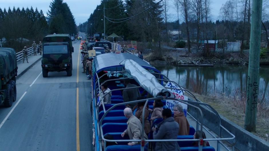 A military truck drives across the bridge past the checkpoint as the military stops a bus of protestors from crossing into town.