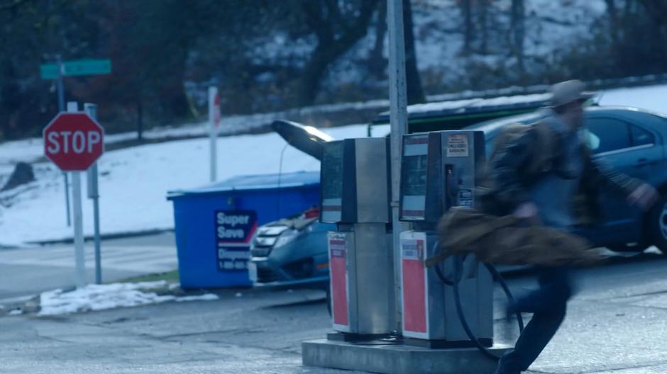 Ben runs past the gas pumps on his way to Maddie and Ryn's hiding place.