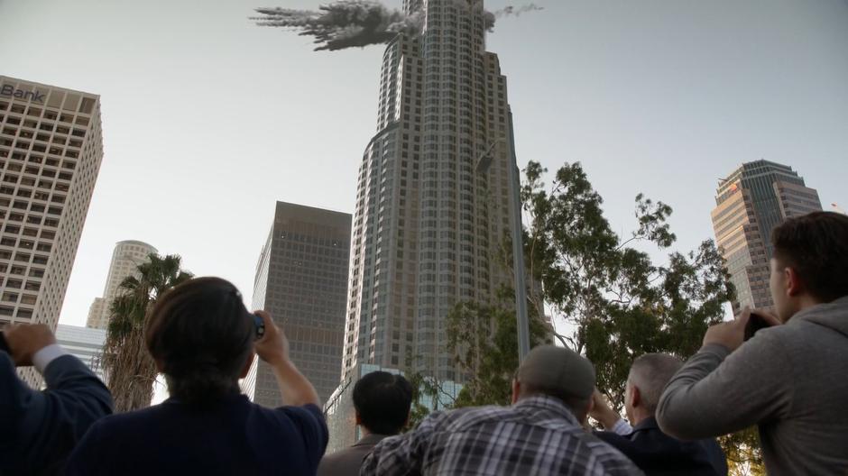 Bystanders watch as the fight between Kara and Astra crashes through a nearby skyscraper.