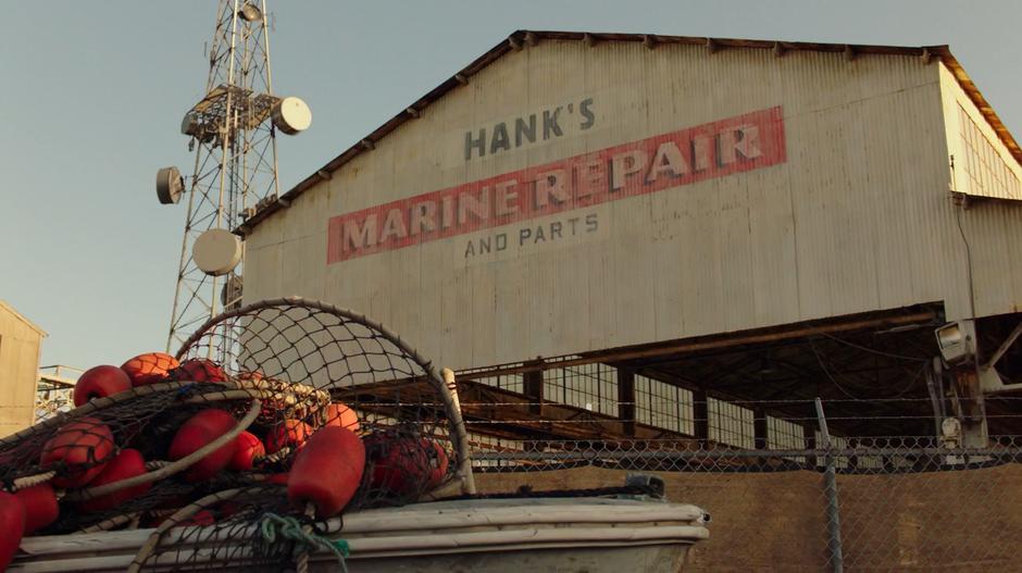 Establishing shot of the sign for Hank's Marine Repair and Parts on the side of the building.