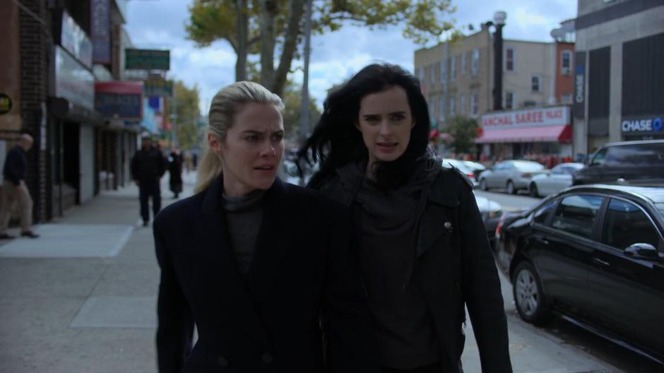 Jessica pulls Trish down the street away from the two detectives.