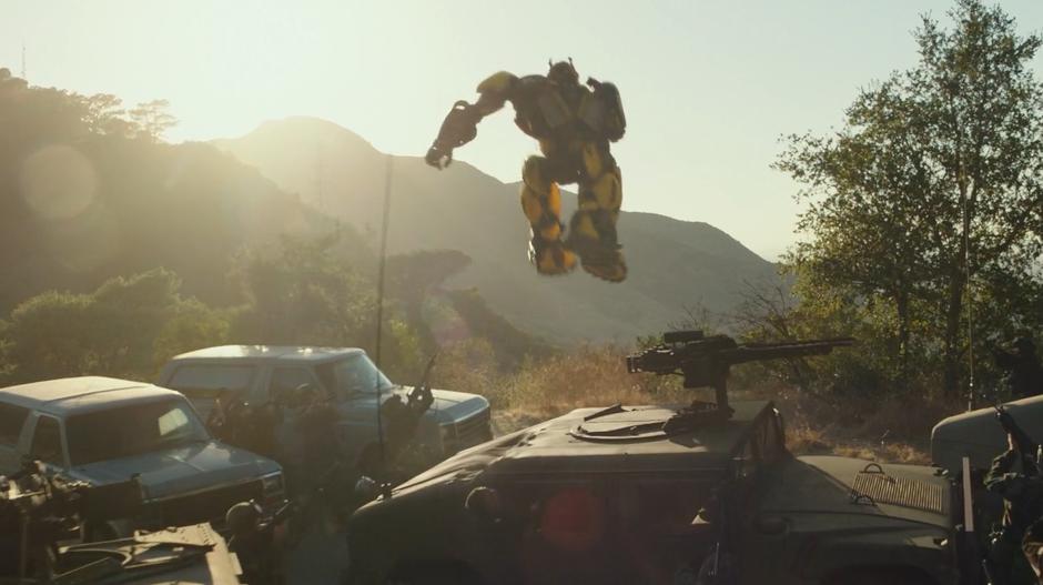 Bumblebee leaps over the side of the hill as the soldiers follow him with their guns.