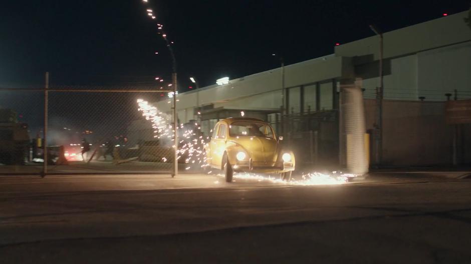 Bumblebee crahes through the gate and onto the street with Charlie as soldiers fire after him.