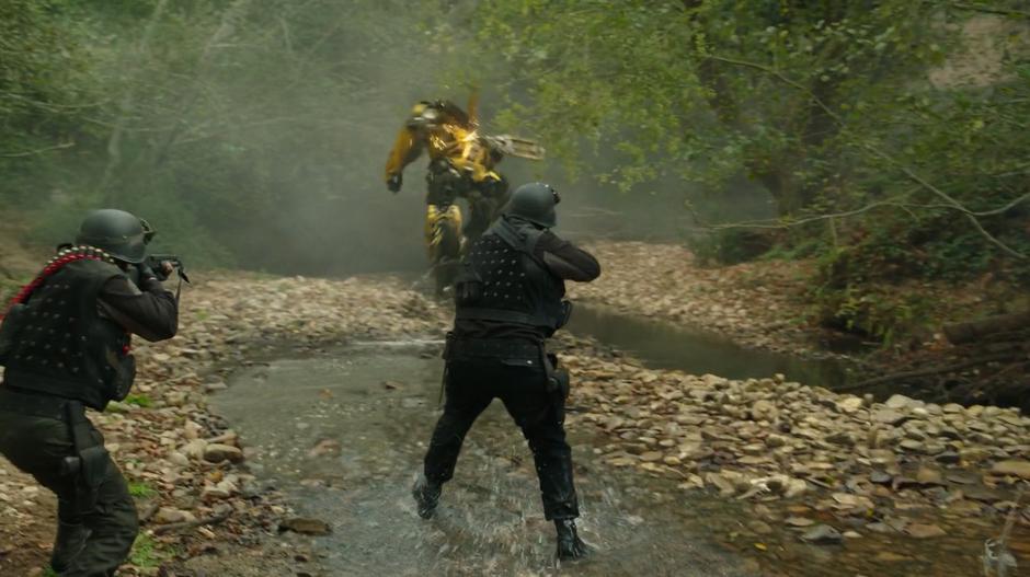 Two soldiers fire at Bumblebee as he runs down a stream bed.