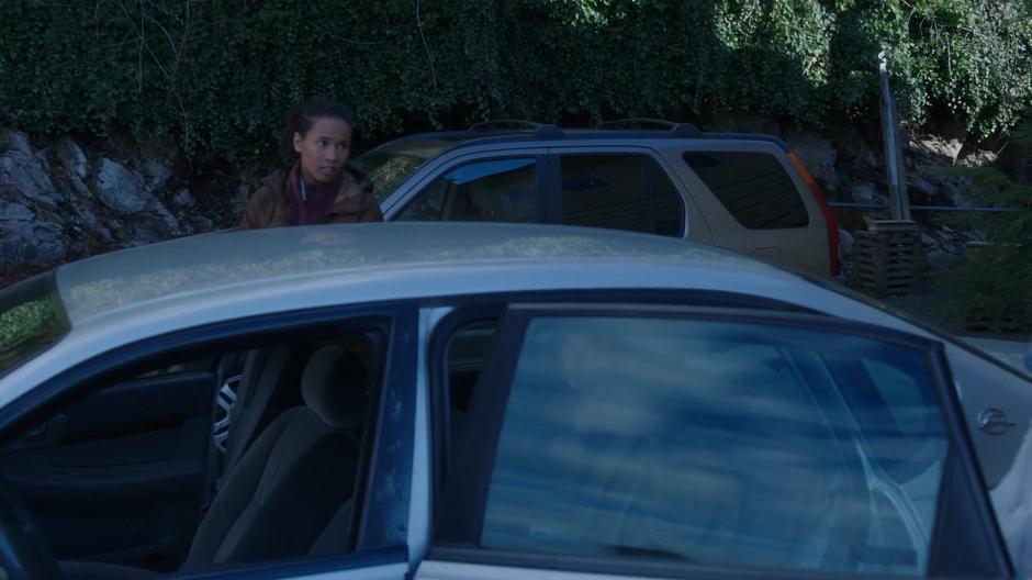 Maddie watches Ben approach the car while Ryn sits inside.