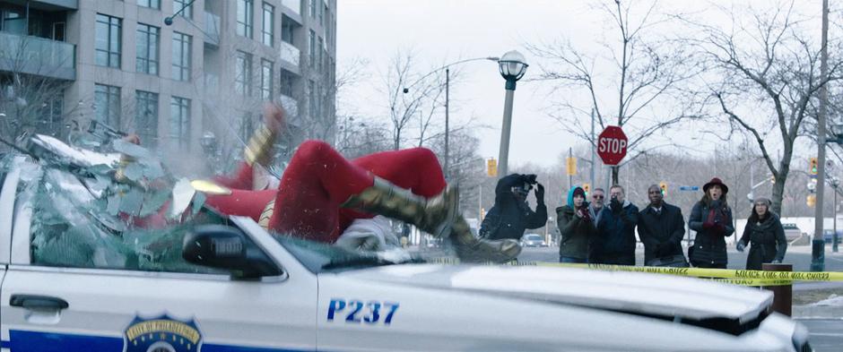 Billy smashes into the roof of a police car after being punched by Sivana.