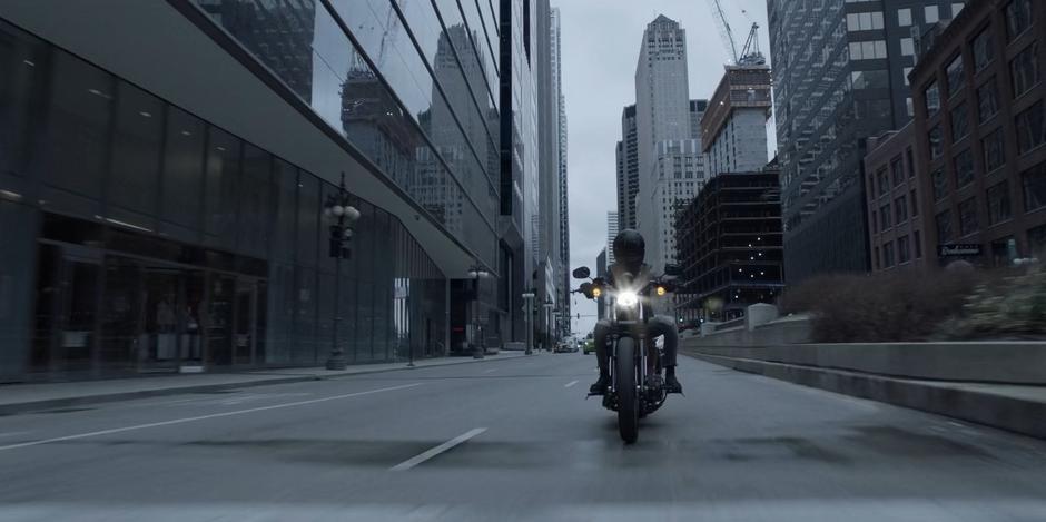 Kate rides her motorcycle through downtown after arriving in the city.