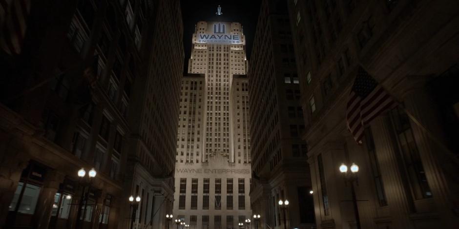 The Wayne Enterprises building sits illuminated at the end of the street.