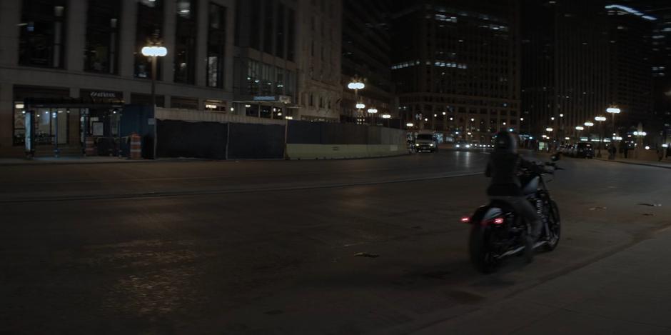 Kate rides her motorcycle away from the Crows Security Headquarters.
