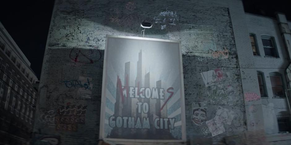 A "Welcome to Gotham City" advertisment is covering in graffiti.