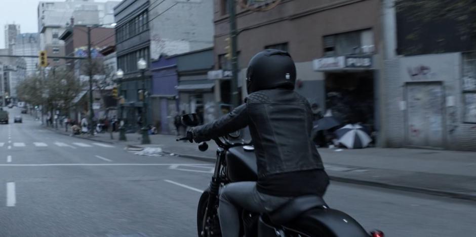 Kate rides her motorcycle towards downtown.