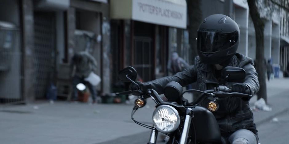 Kate rides her motorcycle through the streets after arriving back in the city.