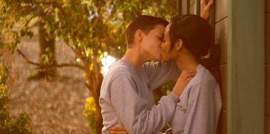 Kate and Sophie kiss while leaning against the side of the building.