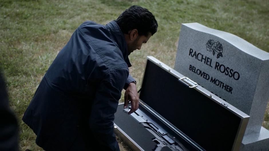 Ramsey kneels down in front of his mother's grave and examines the gun.