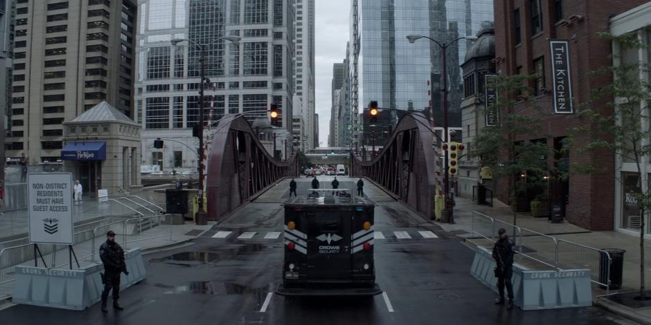 A Crows Security armored truck approaches the checkpoint on the bridge leading to the affluent district of the city.