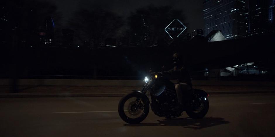 Kate rides her motorcycle down the street at night.