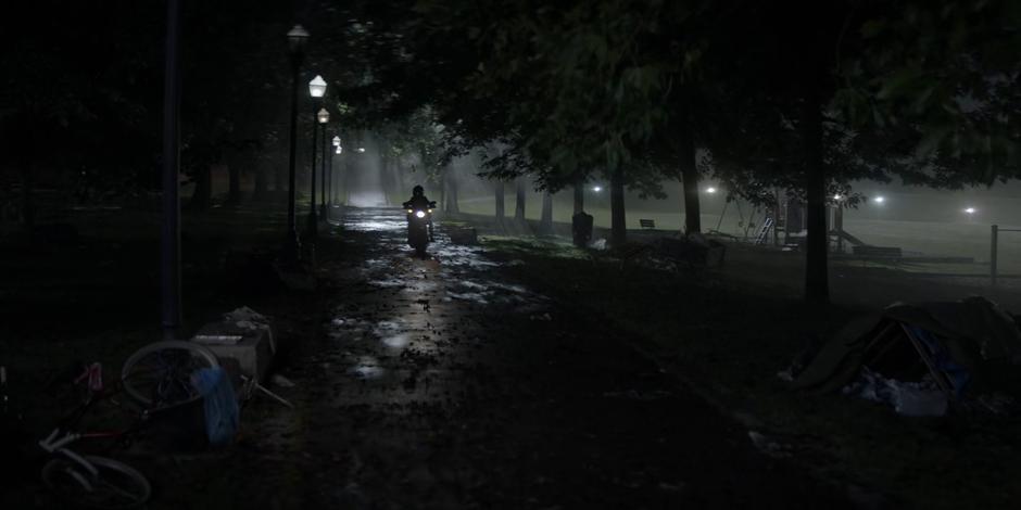 Kate rides her motorcycle down the path through the path at night.