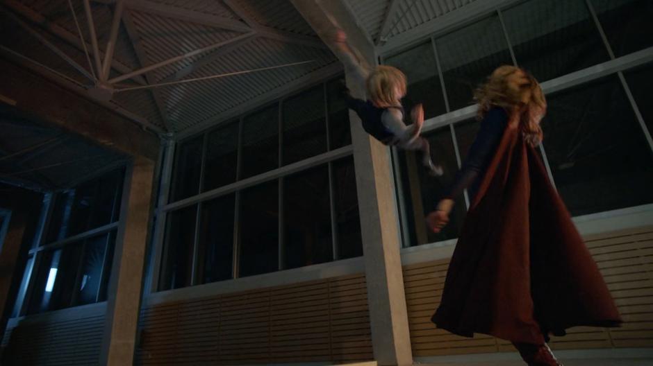 Caroline O'Conner flips through the air while fighting Kara high above the floor.