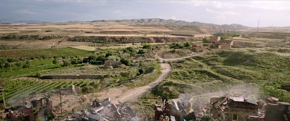 Fury and Hill's car drives down a dirt road towards the destroyed town.