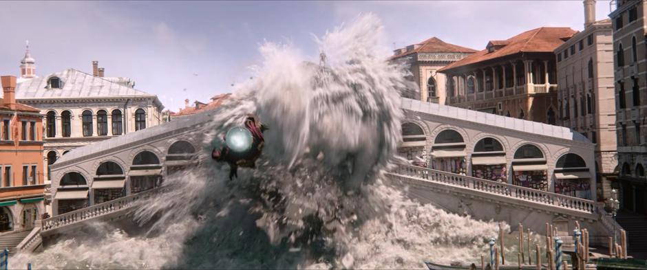 Mysterio flies ahead of the elemental as it crashes through the bridge.