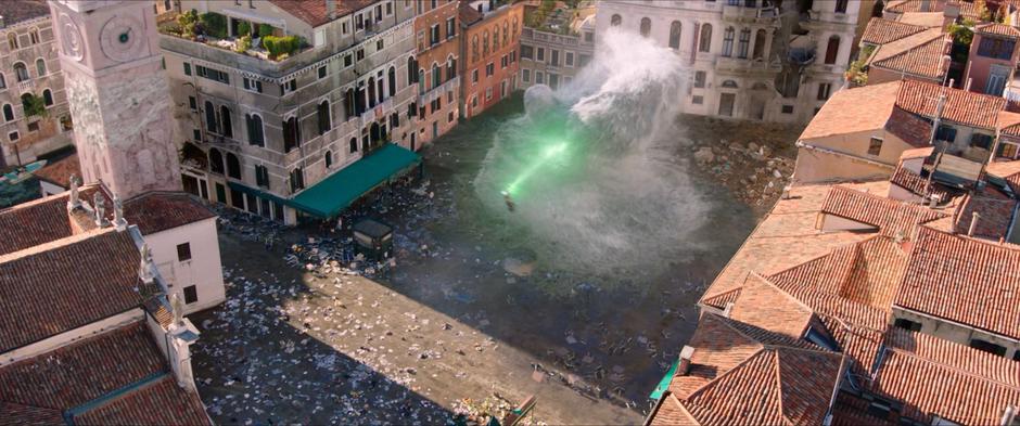 Mysterio shoots a blast at the water elemental in the middle of the trashed square.