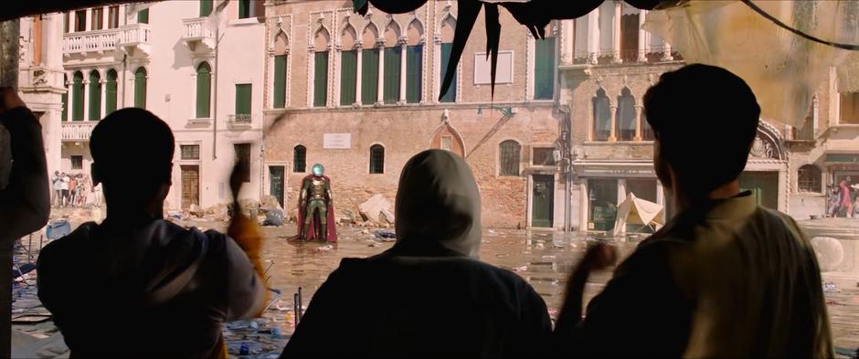 The studens and other bystanders cheer for Mysterio as he stand triumphant in the middle of the square.