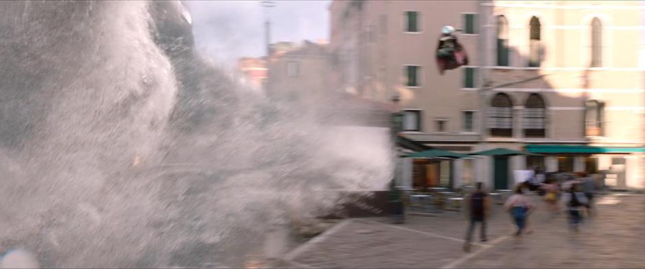 The group runs across the plaza as Mysterio fights the water elemental overhead.