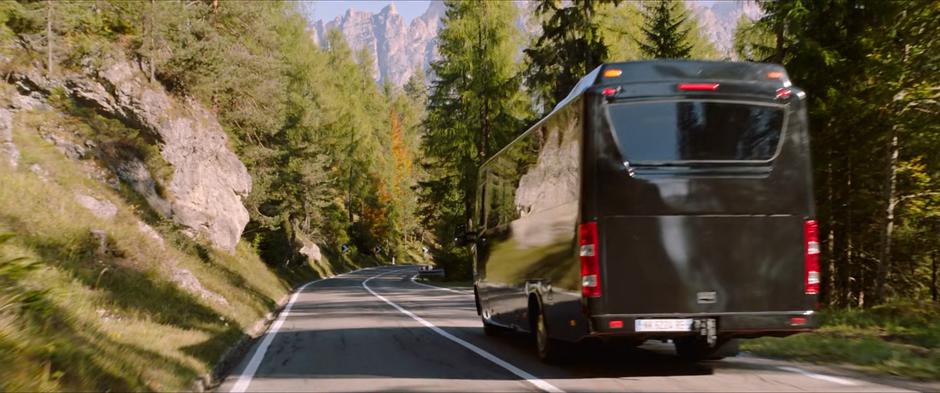The tour bus drives down a forested road.