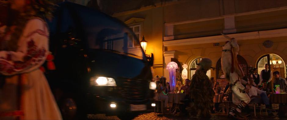 The tour bus drives through the busy nighttime streets of Prague.