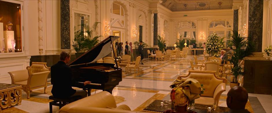 The group enters the lobby of the hotel where there is a live piano player.