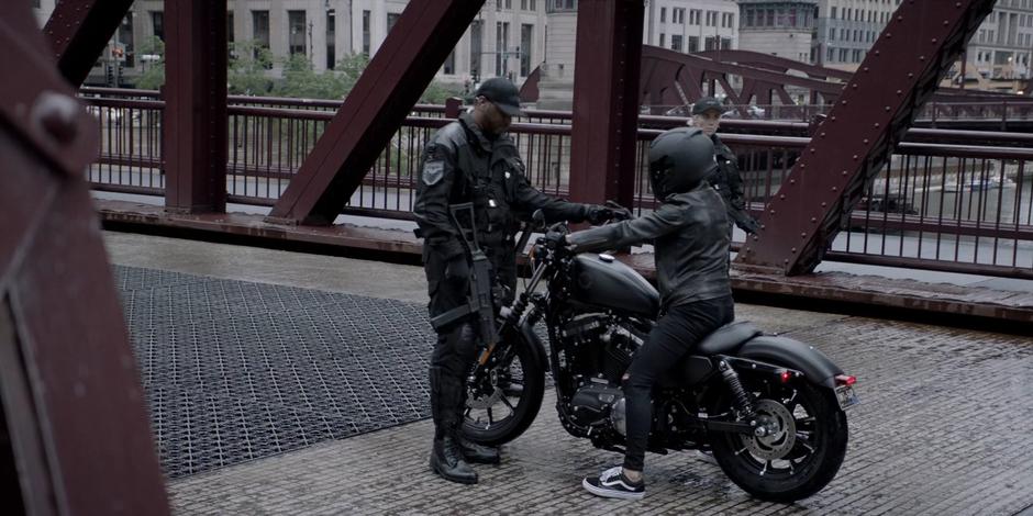 A Crows Security guard checks Kate's credentials as she travels through the checkpoint on her motorcycle.