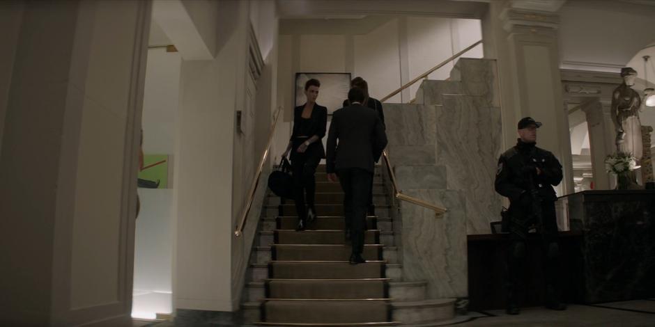 Kate walks down the stairs from the roof carrying her bag of supplies.