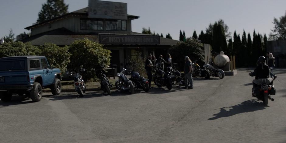 Kate's car sits parked in front of the diner which is surrounded by bikers.