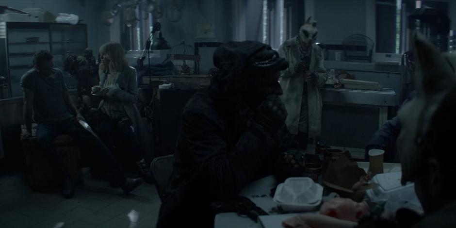 Alice talks to Dodgson while her gang members eat dinner.