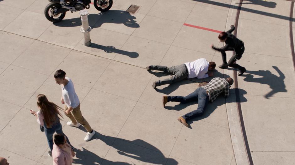 Alex runs over to some people who have fallen over to protect them from the collapsing crane.