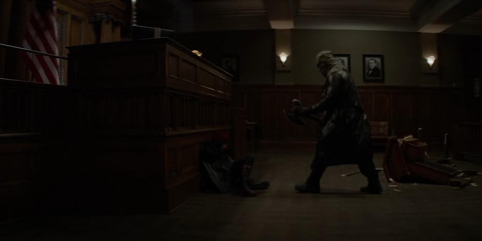 The Executioner approaches Kate who is on the ground in front of the judge's stand.